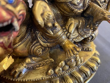 A Tibetan gilt bronze group of Jambhala on his lion, 19/20th C.