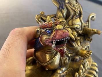 A Tibetan gilt bronze group of Jambhala on his lion, 19/20th C.