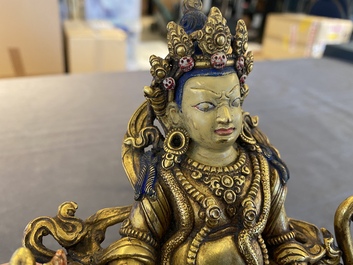 A Tibetan gilt bronze group of Jambhala on his lion, 19/20th C.