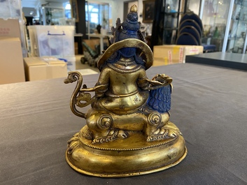 A Tibetan gilt bronze group of Jambhala on his lion, 19/20th C.