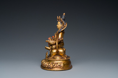 A Tibetan gilt bronze group of Jambhala on his lion, 19/20th C.