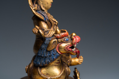 A Tibetan gilt bronze group of Jambhala on his lion, 19/20th C.
