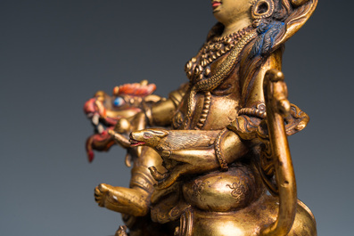A Tibetan gilt bronze group of Jambhala on his lion, 19/20th C.