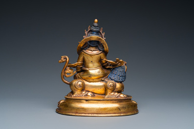 A Tibetan gilt bronze group of Jambhala on his lion, 19/20th C.