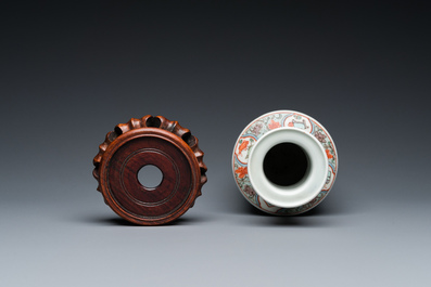 A Chinese famille verte rouleau vase on wooden 'lotus' stand, probably 19th C.