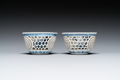 A pair of Chinese blue and white reticulated double-walled cups and saucers, Kangxi