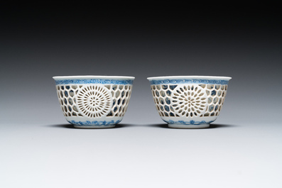 A pair of Chinese blue and white reticulated double-walled cups and saucers, Kangxi