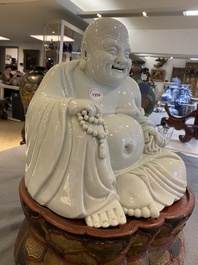 A Chinese blanc de Chine Buddha on lacquered and gilded wooden 'lotus' stand, Qianlong/Jiaqing