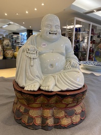 A Chinese blanc de Chine Buddha on lacquered and gilded wooden 'lotus' stand, Qianlong/Jiaqing