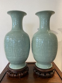 A pair of Chinese monochrome celadon-glazed vases with underglaze design on wooden stands, Qianlong mark, 18/19th C.