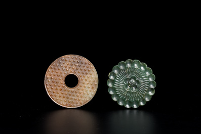 Un disque 'bi' en jade c&eacute;ladon et rouille et un pendentif en forme de fleur en jade vert sur socles en bois, Ming et Qing