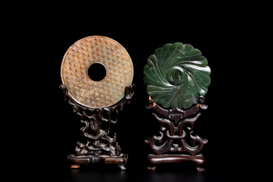 Un disque 'bi' en jade c&eacute;ladon et rouille et un pendentif en forme de fleur en jade vert sur socles en bois, Ming et Qing