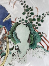 A Chinese famille verte dish with a lady in a garden and a boy offering her a 'jue' vessel, Kangxi