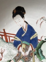 A Chinese famille verte dish with a lady in a garden and a boy offering her a 'jue' vessel, Kangxi