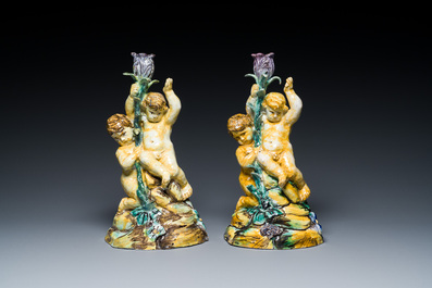 A pair of polychrome Talavera pottery candlesticks with putti on a branch, Spain, 18th C.