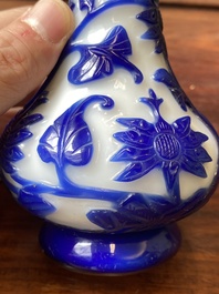 A Chinese overlay Beijing glass bottle vase with lotus scrolls in blue on white, 19th C.