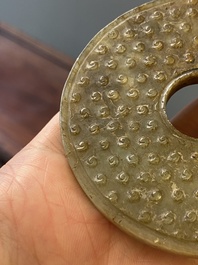 Un disque 'bi' en jade c&eacute;ladon et rouille et un pendentif en forme de fleur en jade vert sur socles en bois, Ming et Qing