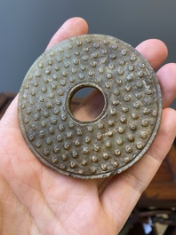 Un disque 'bi' en jade c&eacute;ladon et rouille et un pendentif en forme de fleur en jade vert sur socles en bois, Ming et Qing