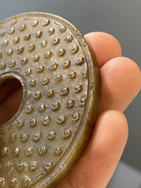 Un disque 'bi' en jade c&eacute;ladon et rouille et un pendentif en forme de fleur en jade vert sur socles en bois, Ming et Qing