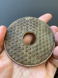 Un disque 'bi' en jade c&eacute;ladon et rouille et un pendentif en forme de fleur en jade vert sur socles en bois, Ming et Qing