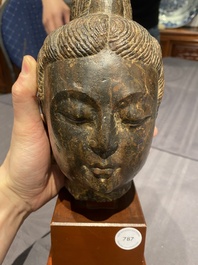 Een Chinees bruin-grijs kalkstenen hoofd van Bodhisattva, wellicht Tang