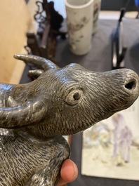 Een Chinese monochrome sculptuur van een liggende waterbuffel op houten sokkel, 19e eeuw