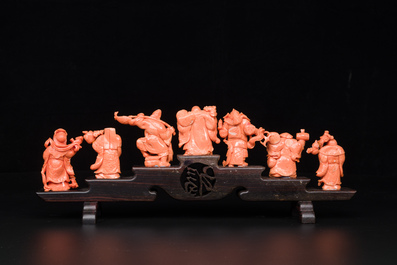 A set of seven Chinese red coral figures on wooden stand, 19/20th C.