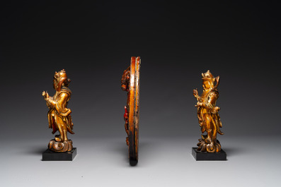 A pair of Chinese gilt-lacquered wooden guardians and a round 'dragon' plaque, 19th C.