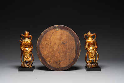 A pair of Chinese gilt-lacquered wooden guardians and a round 'dragon' plaque, 19th C.