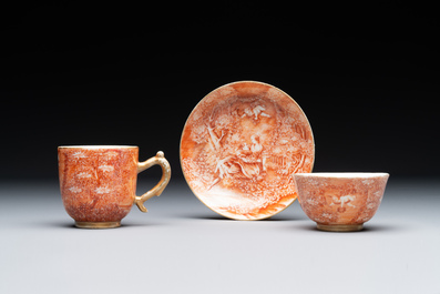Two rare Chinese iron-red-decorated 'European scene' cups and a saucer, Qianlong