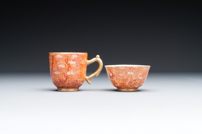 Two rare Chinese iron-red-decorated 'European scene' cups and a saucer, Qianlong