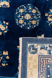 Een groot Chinees donkerblauw tapijt met bloemen en vlinders, 19/20e eeuw
