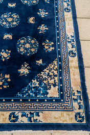 Een groot Chinees donkerblauw tapijt met bloemen en vlinders, 19/20e eeuw