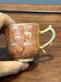 Two rare Chinese iron-red-decorated 'European scene' cups and a saucer, Qianlong