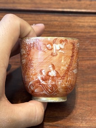 Two rare Chinese iron-red-decorated 'European scene' cups and a saucer, Qianlong