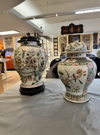 Two Chinese famille verte covered vases on wooden stands, 19th C.
