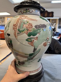 Two Chinese famille verte covered vases on wooden stands, 19th C.