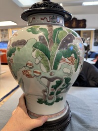 Two Chinese famille verte covered vases on wooden stands, 19th C.