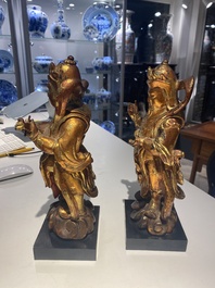 A pair of Chinese gilt-lacquered wooden guardians and a round 'dragon' plaque, 19th C.