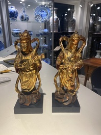 A pair of Chinese gilt-lacquered wooden guardians and a round 'dragon' plaque, 19th C.