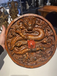 A pair of Chinese gilt-lacquered wooden guardians and a round 'dragon' plaque, 19th C.