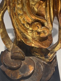 A pair of Chinese gilt-lacquered wooden guardians and a round 'dragon' plaque, 19th C.