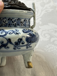 Een Chinees blauw-wit wierookvat op drie poten met floraal decor en een houten deksel, Ming