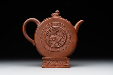 A Chinese circle-shaped Yixing stoneware 'kylin' teapot with relief design, Kangxi