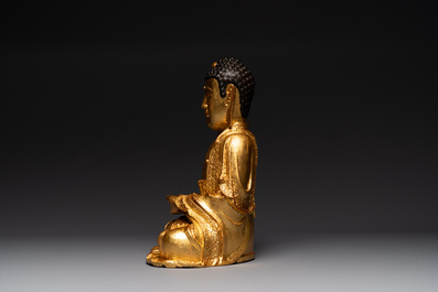 A large Sino-Tibetan gilt bronze Buddha on wooden stand, Ming