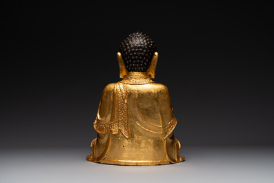 A large Sino-Tibetan gilt bronze Buddha on wooden stand, Ming
