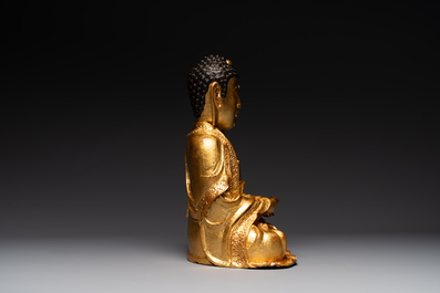 A large Sino-Tibetan gilt bronze Buddha on wooden stand, Ming