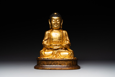 A large Sino-Tibetan gilt bronze Buddha on wooden stand, Ming