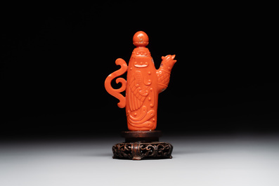 A Chinese carved red coral ewer and cover on wooden stand, 19th C.