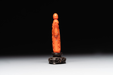 A Chinese carved red coral ewer and cover on wooden stand, 19th C.